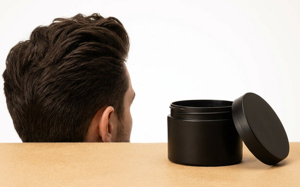 Man met volumineuze quiff naast een matte clay potje, gestyled met grip en textuur