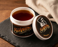 Suavecito Original Hold Pomade - open pot met glanzende inhoud op leisteen