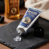 Reuzel Fiber Hair Gel - open tube met heldere gel op leisteen naast grooming tonic