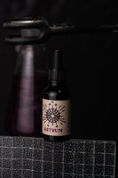 By Elementum Mollis Astrum Beard Oil - flesje op rand met tang en glas op de achtergrond