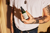 Pomp & Co. Beard Oil - man in wit shirt houdt het flesje vast
