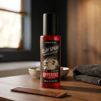 Uppercut Clay Spray - flacon bij houten kam en handdoek op wastafelblad